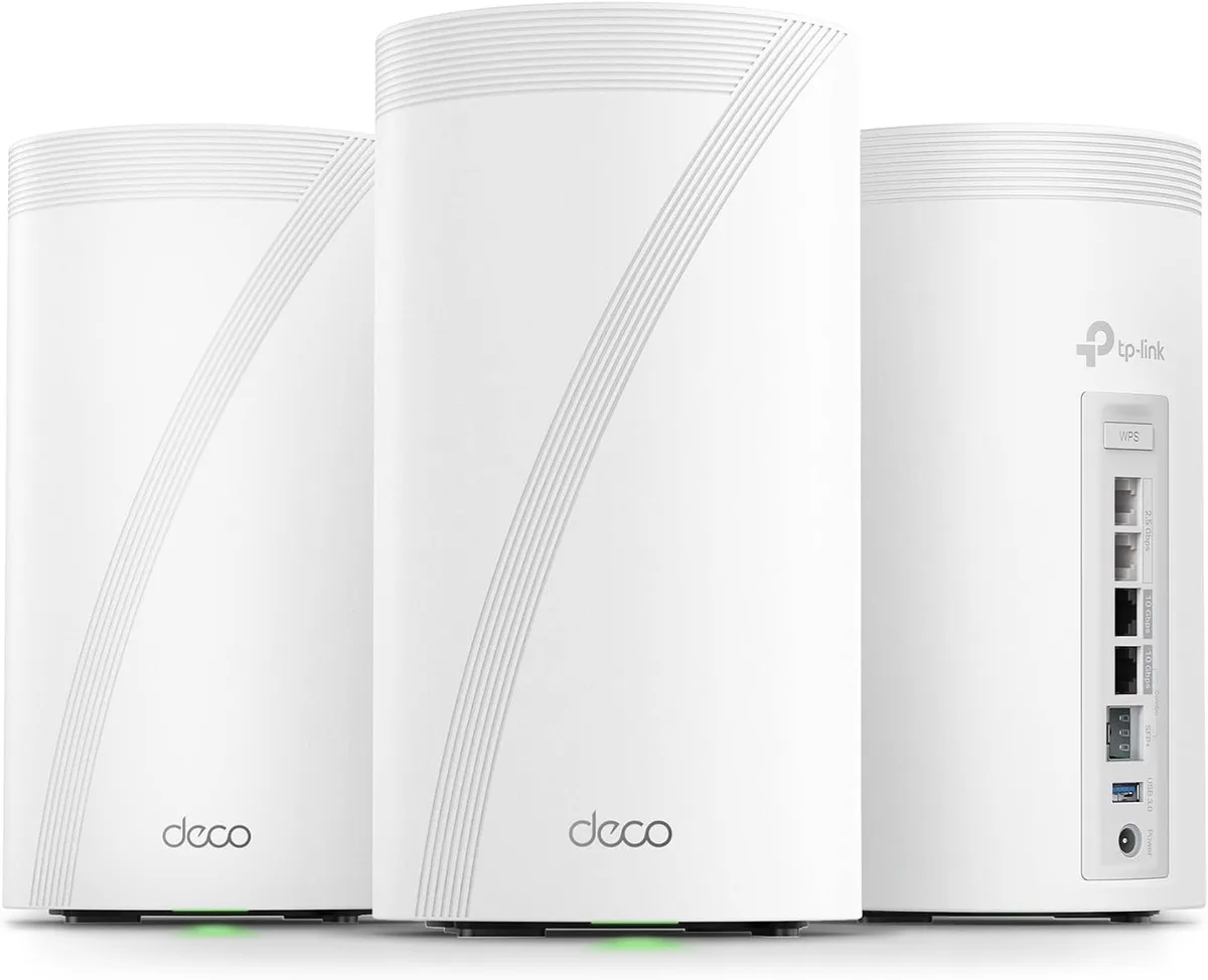 Three white cylindrical TP-Link Deco BE85 mesh units photographed against a white background, each with a curved ribbed seam down the front and the deco wordmark near the base, with the rightmost unit turned to show its rear port column labelled WPS, two 2.5 Gbps jacks, two 10 Gbps jacks with the lower one marked Combo, an SFP plus cage, a USB 3.0 port and the power inlet